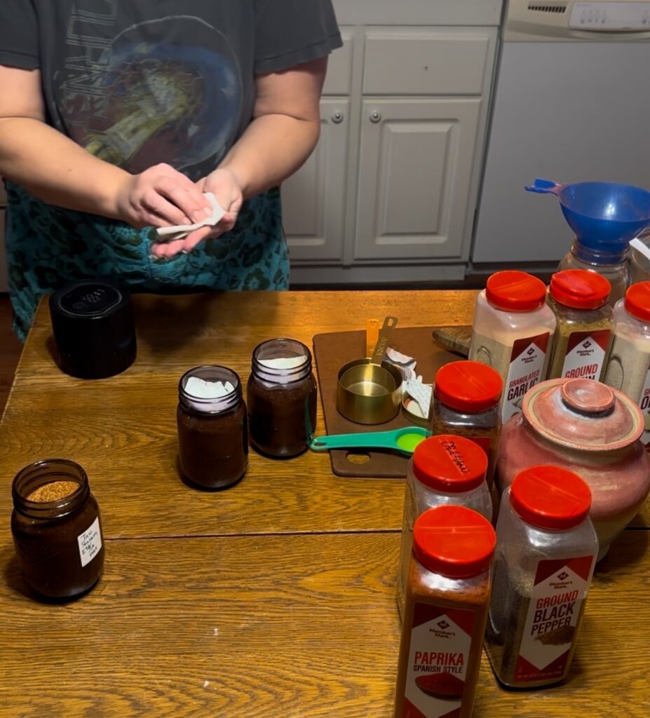 lady wiping jar lids with taco seasoning on table. 