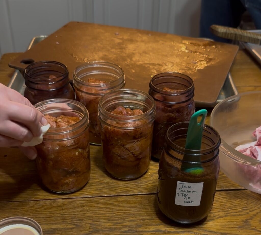wiping rims of canning jars filled with seasoned pork loin
