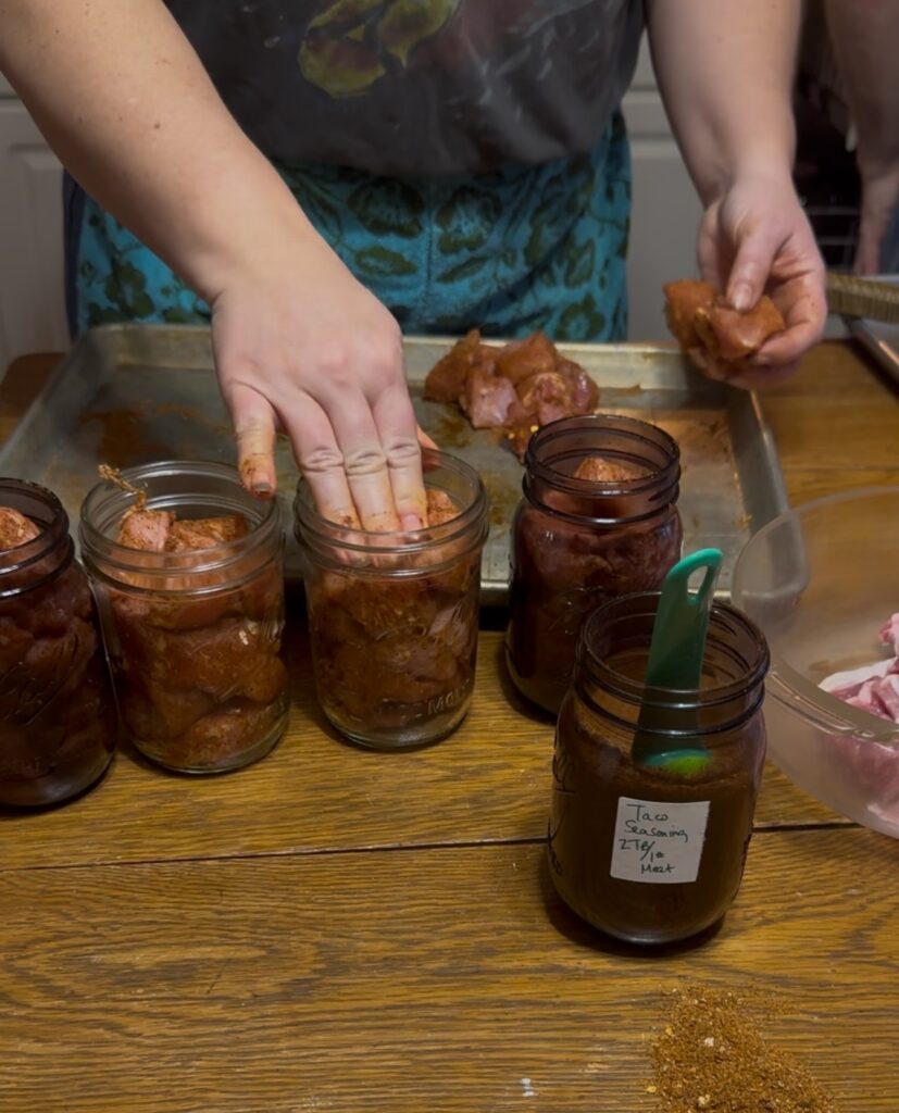 lady stuffing canning jars with seasoned pork loins